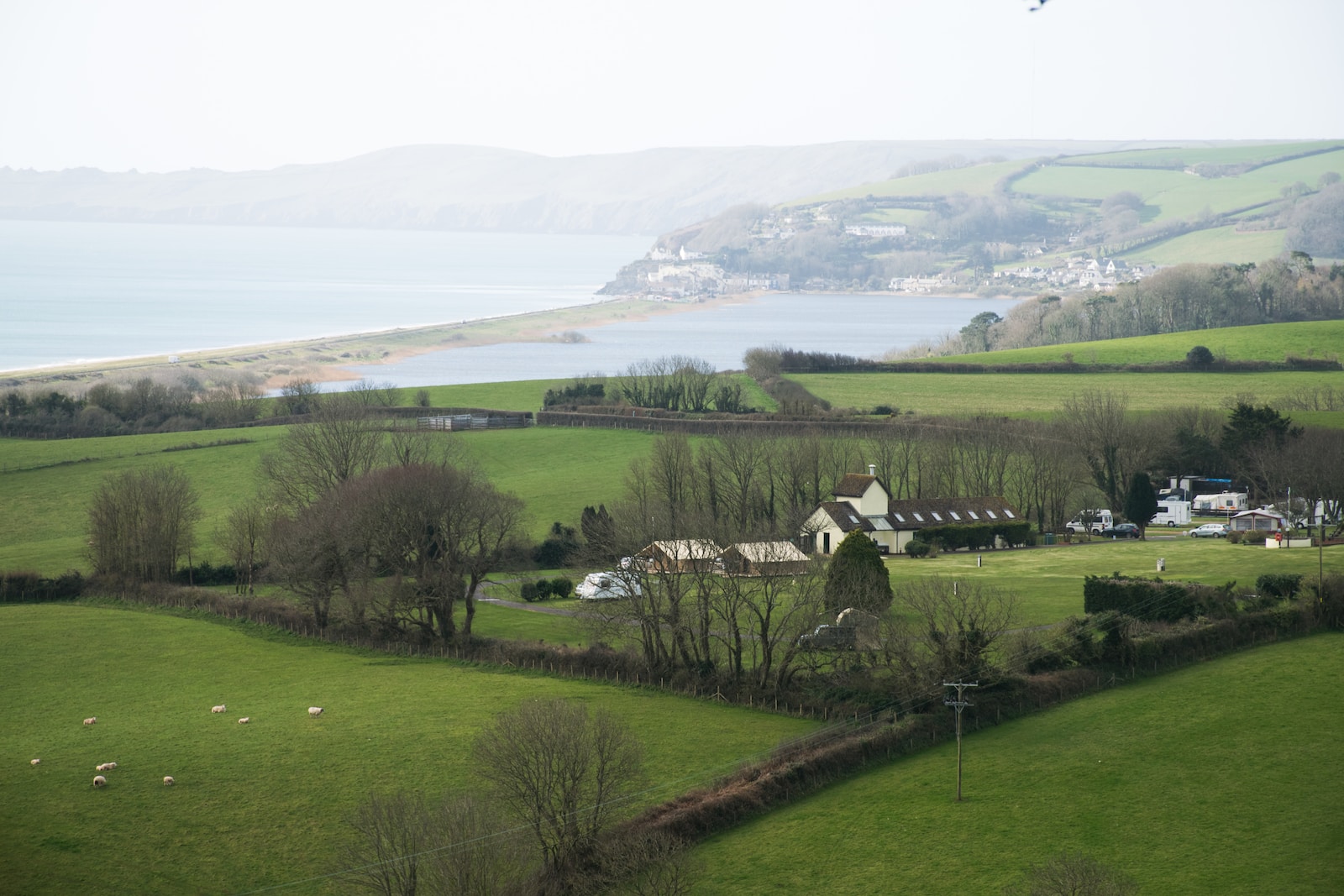 a green field with a house and a lake in the background